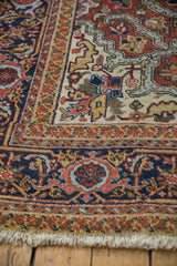 Vintage Heriz carpet's ivory fringe and bold red, navy, gold geometric border.
