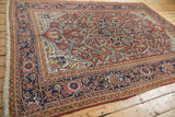 Vintage Heriz carpet corner with navy and brick red borders, ivory fringe, and visible knot heads.
