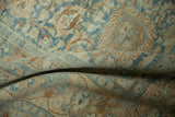 Soft folds of a distressed Khoy carpet showing the low, even-worn pile and pale blue floral motifs.