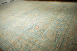 A low angle on a distressed Khoy carpet showing its soft blue and apricot floral field.