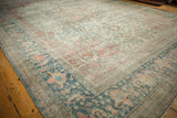 Low angle showing the decorative wear on a vintage Mahal carpet's blue floral border and ivory field.
