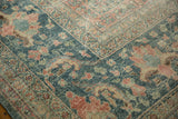 Worn, hand-knotted texture on the corner of a vintage Mahal carpet in faded teal and red.