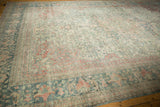 A distressed Mahal carpet's time-softened pile and floral border in dusty blue and faded red.