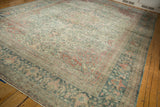 Angled view of the distressed Mahal carpet's corner, with time-softened florals and a dusty blue border.