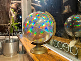 Angled view of vintage 1990s holographic globe, highlighting prismatic rainbow effects and gold stand.
