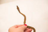 Vintage iron snake held by hand, with rustic texture and aged patina.