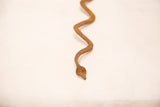 Close-up of the hand-forged Lobi iron snake head and winding body with aged patina.