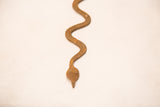 Vintage iron snake close-up, highlighting handmade form and weathered iron texture.