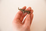 A vintage mini bronze rhino held in hand to show its small collectible size.