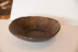 Close-up of the hand-carved primitive texture inside a dark brown vintage wooden bowl.
