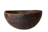 Vintage hand-carved African wooden bowl with primitive geometric patterns and dark wood character.