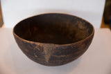 Hand-carved African wooden bowl detail, highlighting its distinct crack and primitive texture.