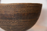 Vintage African wooden bowl detail, showing hand-carved zigzag patterns and dark patina.