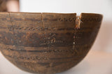 Primitive hand-carved wooden bowl showing deep crack with wire repair and red patching.
