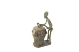 Vintage African oxidized copper drummer showing its textured, handmade details and patina.