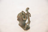 Side profile of the vintage African drummer's stylized, slender copper figure.