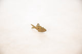 The textured side of a vintage bronze fish pendant showing a spiral wire motif.