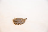 Angled view of a vintage African bronze pendant showing its textured, aged patina.