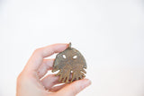 Handmade African bronze jellyfish pendant held to show its scale and unique texture.