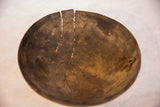 Vintage African wooden bowl showing prominent cracks and metal repairs.