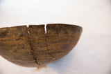 Primitive African wooden bowl with zig-zag repair stitches across a deep crack and incised horizontal lines.