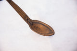 Close-up of vintage African wooden spoon bowl with carved lines, patterned handle, and metal repair.