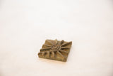 Angled detail of a vintage bronze coin showing its raised spiral sunburst and dark patina.