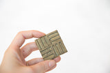 Square vintage African bronze coin with a textured, raised geometric design.