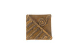 Vintage square African bronze coin with a rustic, handmade spiral and line motif.