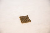 Angled view of the vintage bronze coin, highlighting the relief of its stamped pattern.