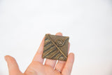 Vintage African square bronze coin held in hand, showing its scale and rustic texture.