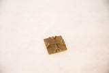A vintage square bronze coin with a raised cross motif and textured, aged patina.