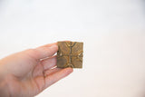 Hand holding the vintage square bronze coin, showing its size and texture.