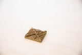 Aged texture and raised geometric motifs on a square African bronze coin.