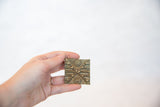 The handheld scale of a vintage African bronze coin with carved geometric patterns.