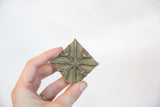 Vintage African square bronze coin held to display its handmade texture and scale.