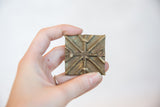 Vintage African bronze coin held in hand, showing its size and rustic texture.