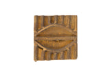 Vintage square African bronze coin with a ridged texture and a central stylized eye design.