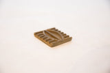 Angled view of a vintage bronze coin highlighting its raised, textured geometric design.