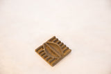 Carved details and handmade texture of a vintage square African bronze coin.