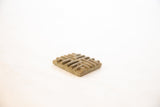 The thick profile and raised geometric pattern of a vintage African bronze coin.