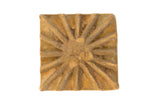 Vintage African square bronze coin with a radiating sunburst relief pattern.