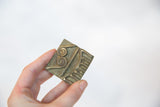Vintage African bronze coin held in hand, showing its scale and handmade texture.