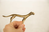 Hand holding a vintage African bronze cheetah, showing its textured surface and aged patina.