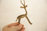 Hand holding a vintage bronze gazelle sculpture, showing its small size and bronze patina.