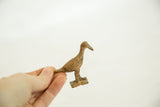 Vintage African bronze bird held in hand to show its small scale and rustic texture.