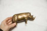 Vintage African bronze rhino with golden patina, held by a hand.