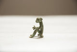 Vintage African oxidized bronze monkey sculpture, seated profile with aged patina.