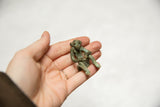 Detailed vintage bronze monkey with oxidized green patina in hand.