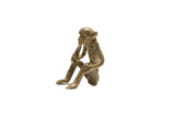 Vintage African bronze sitting monkey figurine eating banana, detailed with aged patina.